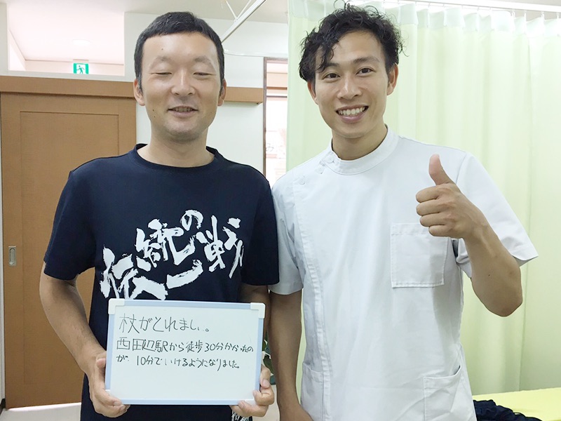 ご来院いただいた方と院長の写真。ボードに「杖がとれました！」